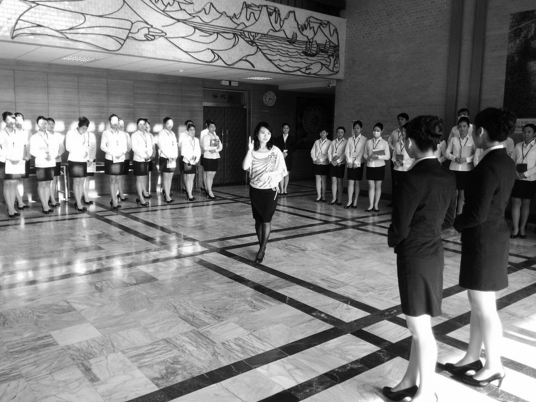 The founder leading a room of ambassadors in training, lined up across a marble hall