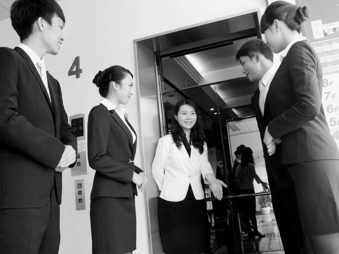 Ambassadors in uniform greeting a guest as she steps out of a lift